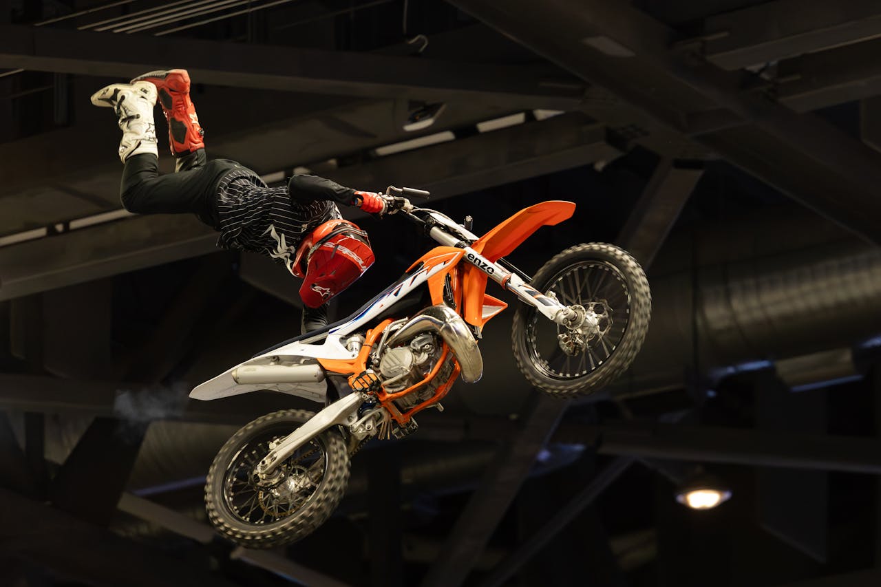 Daring motocross stunt performed mid-air indoors by skilled rider.